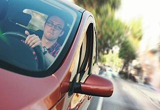 Man with glasses driving a red car ©pexelx.com/JESHOOTS